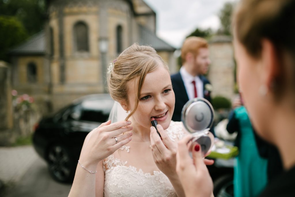 Braut zieht ihren Lippenstift vor dem Hochzeitsshooting nach.