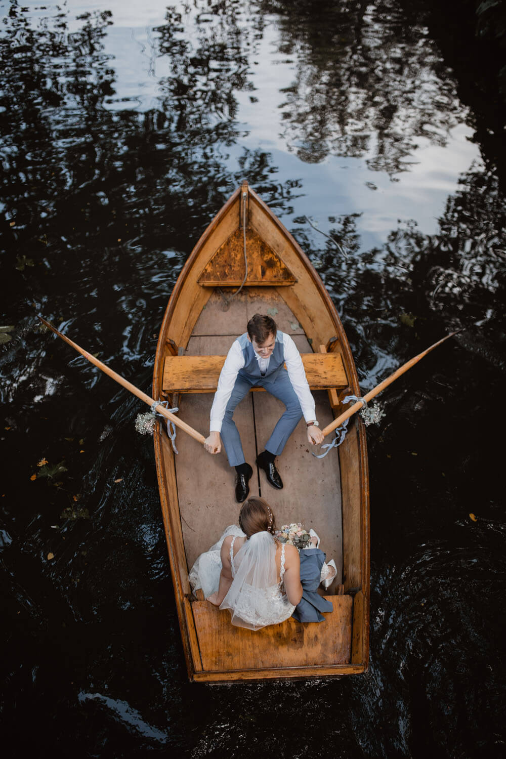 Bräutigam und Braut fahren mit einem Ruderboot.